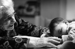 Old lady reaches towards a baby